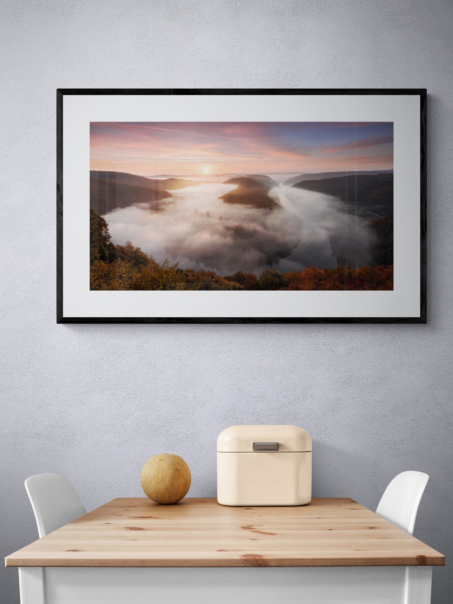 Image Title: The foggy Loop Photographer: Marcus Danz Location: Mettlach, Germany Image description: Mysterious morning fog drifts silently through Mettlach’s Saar loop, partly lit by the warm light of the rising sun. High quality Fine Art print up to 36 inch / around 90 centimeters on Hahnemühle paper available. Large variant over kitchen table.